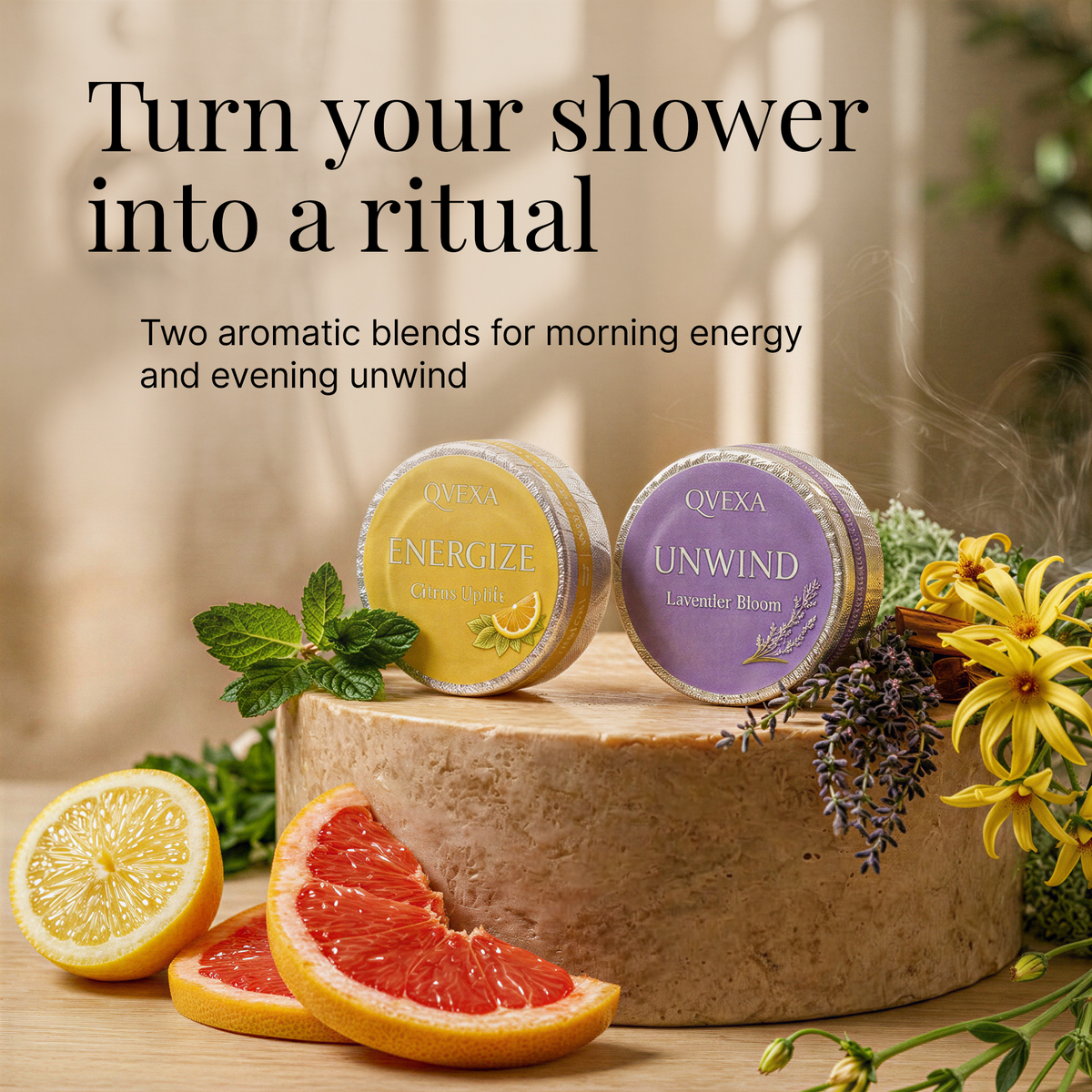 Two round QVEXA bath melts, one yellow labeled Energize and one purple labeled Unwind, displayed on a wooden block with citrus slices, flowers, and mint in a styled setting. Text at the top reads, 'Turn your shower into a ritual' and describes the two aromatic blends.