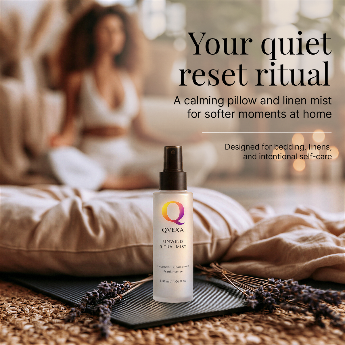 A bottle of QVEXA Unwind Calming Natural Mist stands on a black tray in a cozy bedroom setting, with a blurred woman sitting in the background and text reading 'Your quiet reset ritual.'.